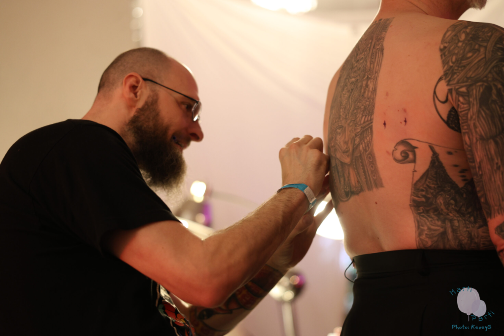 Altered Bodies staff prepare a flyer for a hook suspension by marking piercing points on their back.